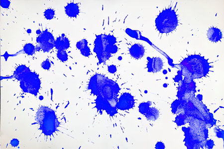 Blue ink splatters on a white background form unique abstract art patterns and designs, showcasing...