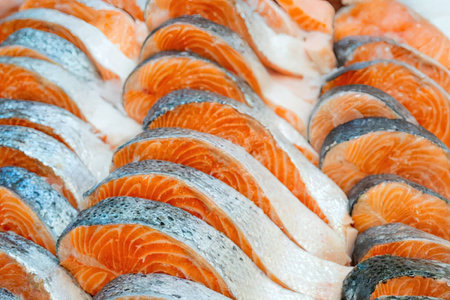 Fresh salmon fillet slices are neatly arranged on a market display showcasing their vibrant orange...
