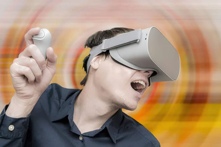 Man wearing virtual reality headset and holding controller with excited expression, symbolizing...
