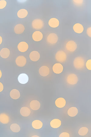 Soft glowing bokeh lights in shades of yellow and orange create a serene atmosphere on a blurred...