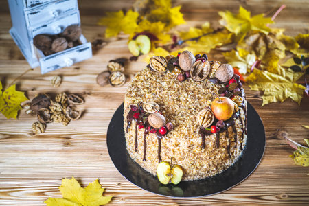Sweet homemade nuts cake with chocolate topping and walnut nuts and apple on wooden vintage table...