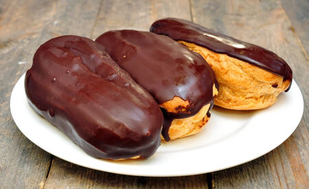 cakes  eclairs  in the plate on wooden table