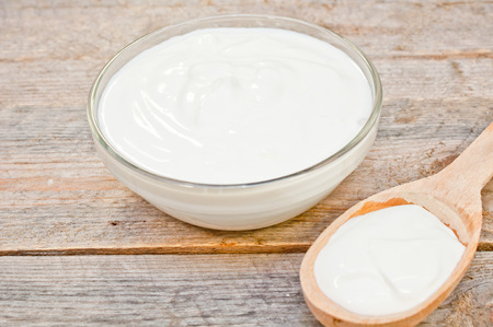 sour cream in a glass bowl and wooden spoonの写真素材