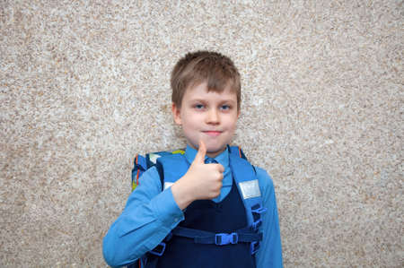 Child with a schoolbag shows the gesture ok.