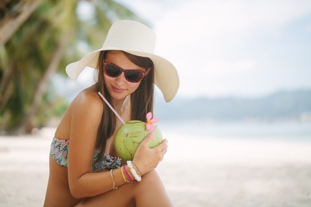 Beautiful woman relaxing on a paradise beach with coconutの写真素材