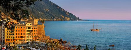 Evening panorama of Camogli with purple sky and sailing shipの写真素材