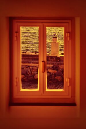 lighthouse sunset view through windowの写真素材