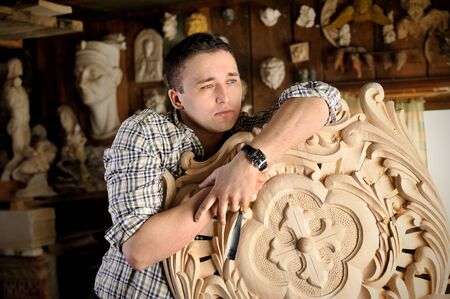 Portrait of young carver in workshop with woodworking