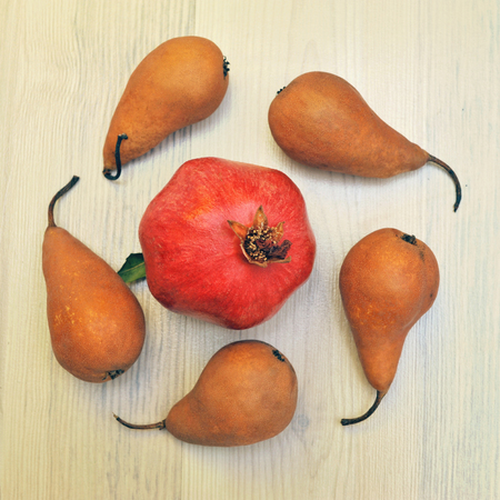 Autumn still life of pear and pomegranate on wooden background.の写真素材