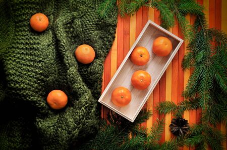 delicious juicy tangerine on green sweater at wooden background.Top view.の写真素材