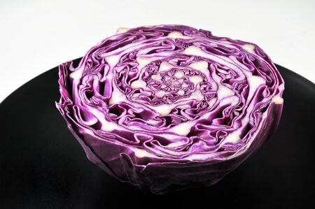 Red cabbage slice isolated on black plate, top viewの写真素材