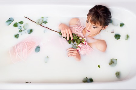 takes a bath with milk and rose petals. Spa treatments for skin rejuvenation