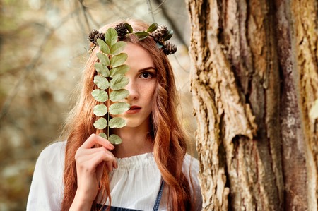 mysterious red hair girl in the wood with leafの写真素材