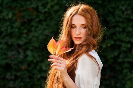 redhead girl autumn portrait with wild grape leafの写真素材
