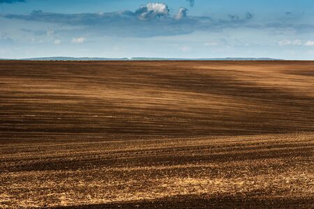 Panorama of arable land over clouds sky