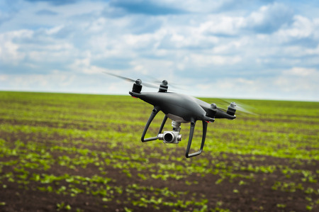 flying drone with build-in camera at cloudly sky under fields