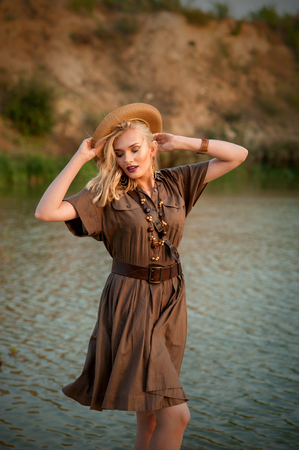 girl in a khaki dress in a safari style and hat circle of waterの写真素材