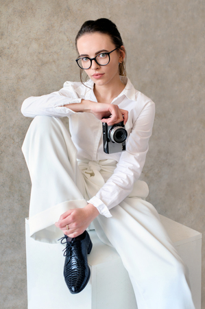 women in white fashion clothes seat on cube with retro cameraの写真素材