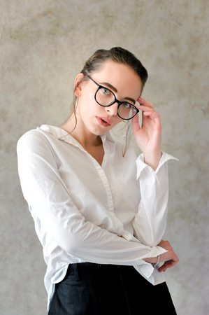 Women in glasses,in white classic shirt near textured backgroundの写真素材