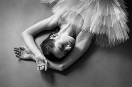young ballerina on the floor of the studio lying down, above black whiteの写真素材
