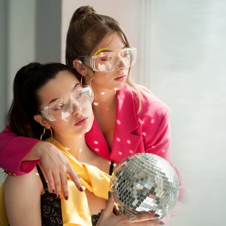Young beautiful womans with bright colorfull spice makeup and discoball . Conceptual color photography. Fashion styleの写真素材
