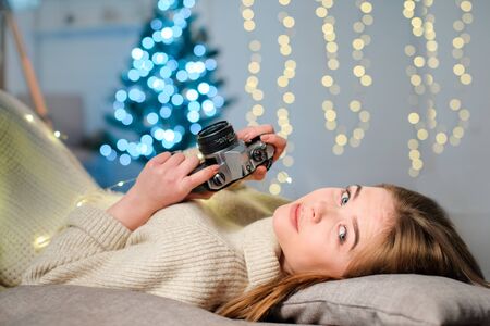 girl with camera lies, Christmas mood, a pretty girl in a white sweaterの写真素材