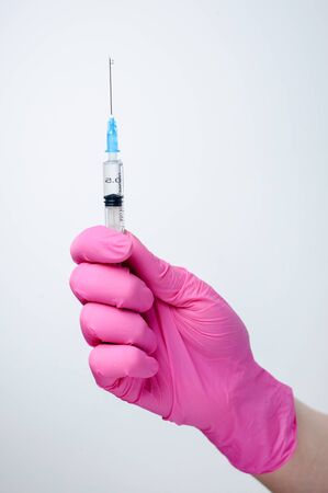 Syringe in hand in medical pink glove. Injectable vaccination. Medicine. Medical procedures