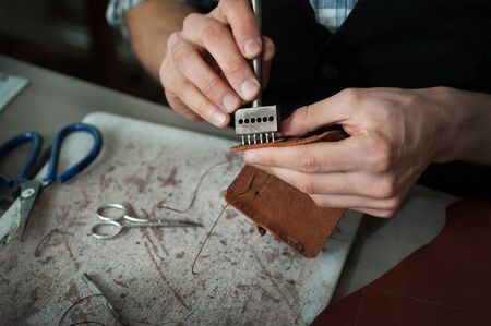 Close up of a leather master working punching holes in genuine leather.