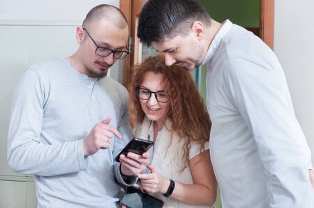 Group of colleagues discussing files on the phone together while at the officeの写真素材