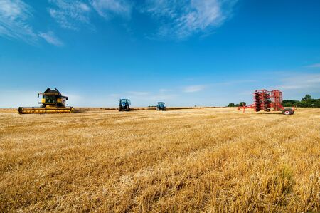 wheat field stubble and machinery combine harvester and tractors on harvesting in Ukraineの写真素材