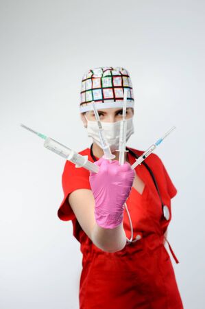 Female doctor holding several syringes in front of face. Girl injection syringe medical interventionの写真素材