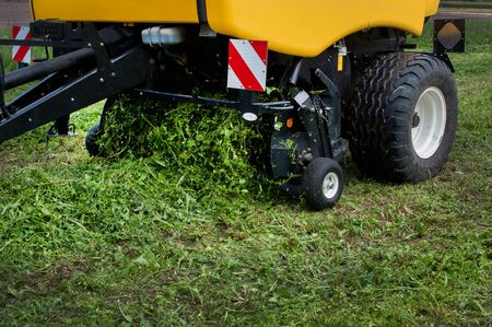 a new baler in motion on the field creates bales at summerの写真素材