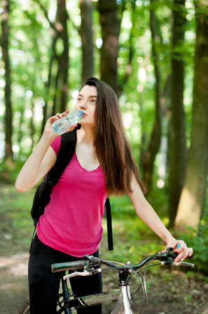 Female cyclist on a bike, with bottle of water, drink, sport women in the forestの写真素材