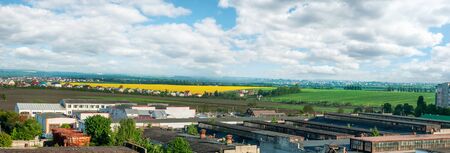 panorama of borders city with Arable lands' blooming rapefield of village nearの写真素材