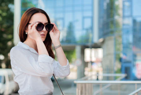 young business lady wears sunglasses on the background of business center, success and careerの写真素材