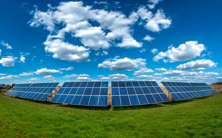 Solar energy panel system power at green field and sky with cloudsの写真素材
