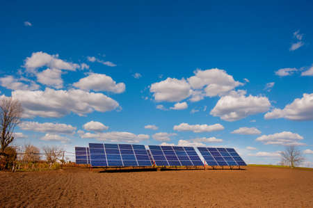 Panel system of solar energy, near the plowed soil of the spring field and beautiful cloudsの写真素材