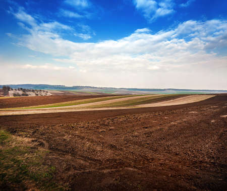 spring field, plowed soil and relief landscape in the backgroundの写真素材