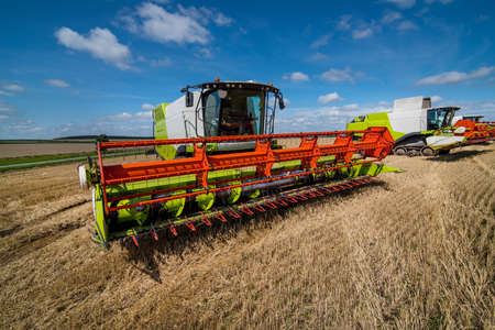 Combine harvesters row close up in wheat field, harvesting. focus on the reaper, top view