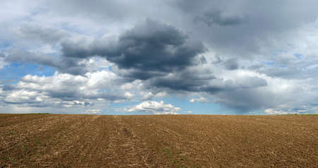 landscape of plowed field in spring under a beautiful sky with cloudsの写真素材