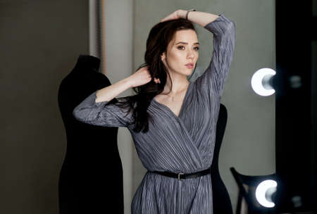 young girl model in a stylish suit standing in her office near mirror, mannequins backgroundの写真素材