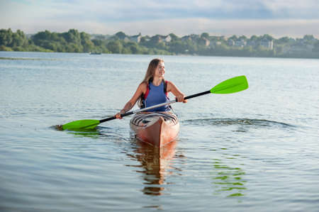 girl rowing a kayak on the lake. A girl in a canoe on a water excursion, active pastime