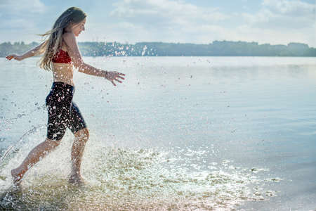 girl running on the shore and splashing waterの写真素材
