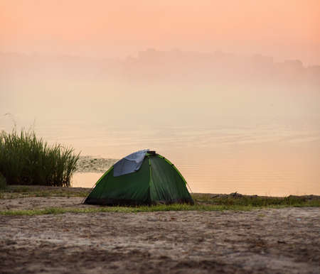 Morning sunrise, dawn, lakeside tent and fogの写真素材