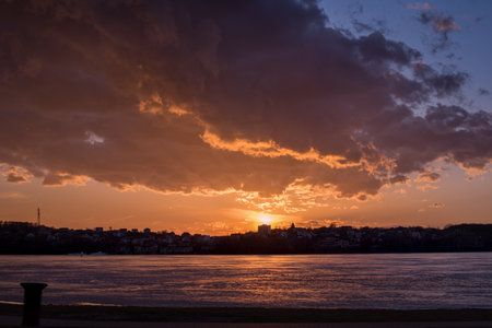 An epic sunset with a crimson sunset. a dramatic sky with clouds over a frozen lake, silhouettes of...