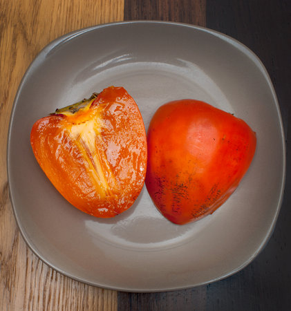 Fresh cut persimmon on a plate on the tableの写真素材