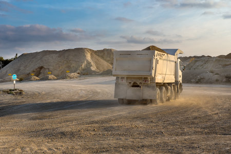 a white truck on a road in a quarry, dust illuminated by the setting sunの写真素材