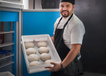 the baker holds a container with dough blanks for storage in the refrigerator