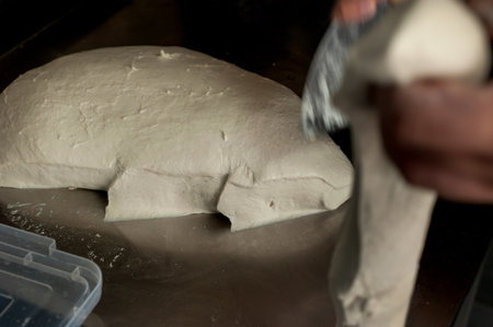 Hands of a male baker measuring pieces of wheat dough for bread