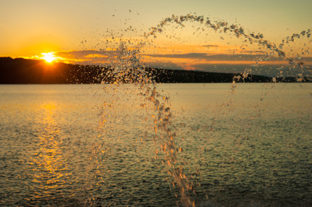 jets of water from the fountains on the pond, against sky of a summer evening.の写真素材